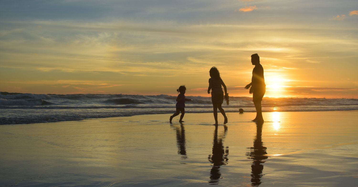 family playing on beach at sunset